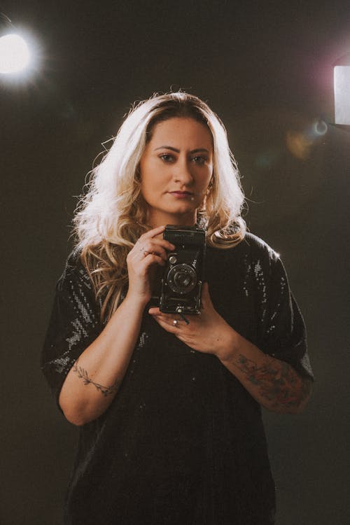 Blonde Woman in Black Dress Posing with Old Camera
