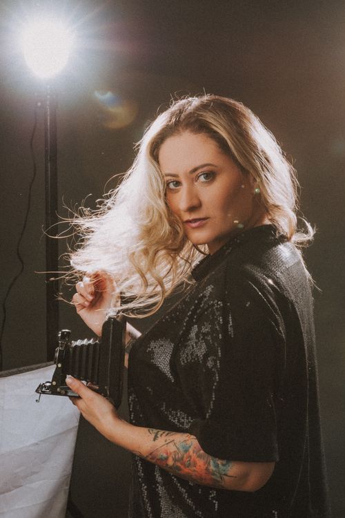 Free Glamorous portrait of woman with tattoo holding an old camera under studio lights. Stock Photo