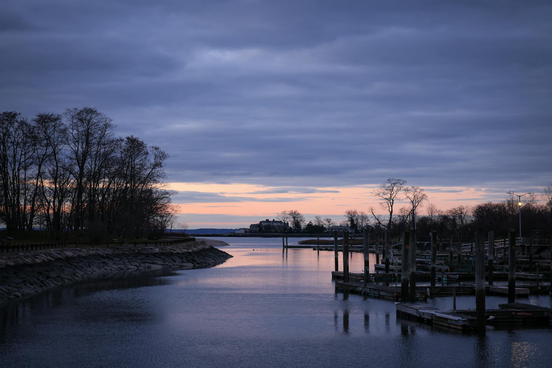 A peaceful winter twilight scene at Cove Island Park dock with a soft pastel sky reflecting on the water.