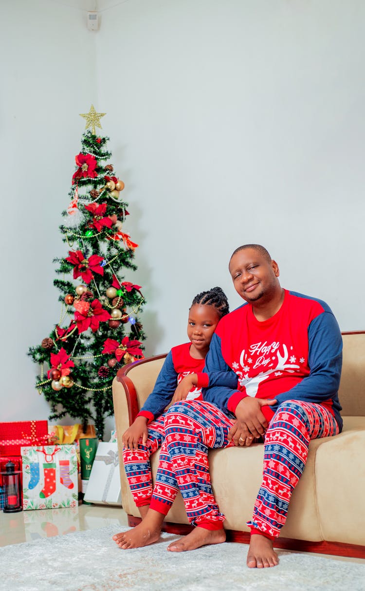 Father And Daughter Sitting By Christmas Tree