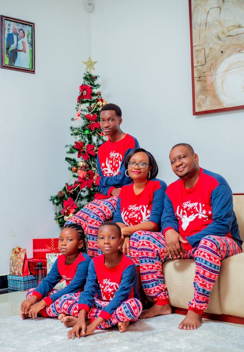 Photo of a Family Wearing Matching Pajamas Sitting by the Christmas Tree