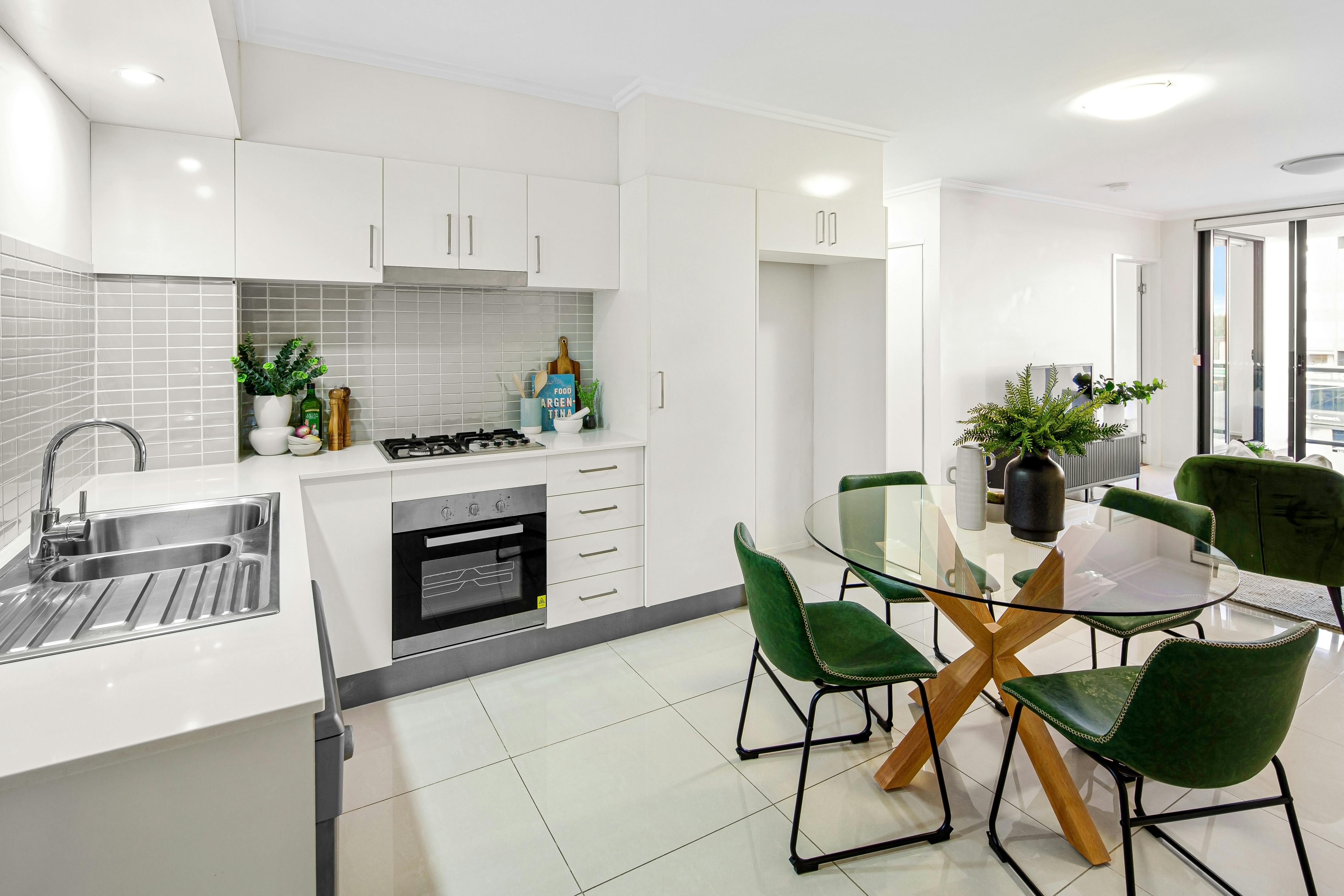 Free A bright, contemporary kitchen and dining space with green chairs and glass table. Stock Photo