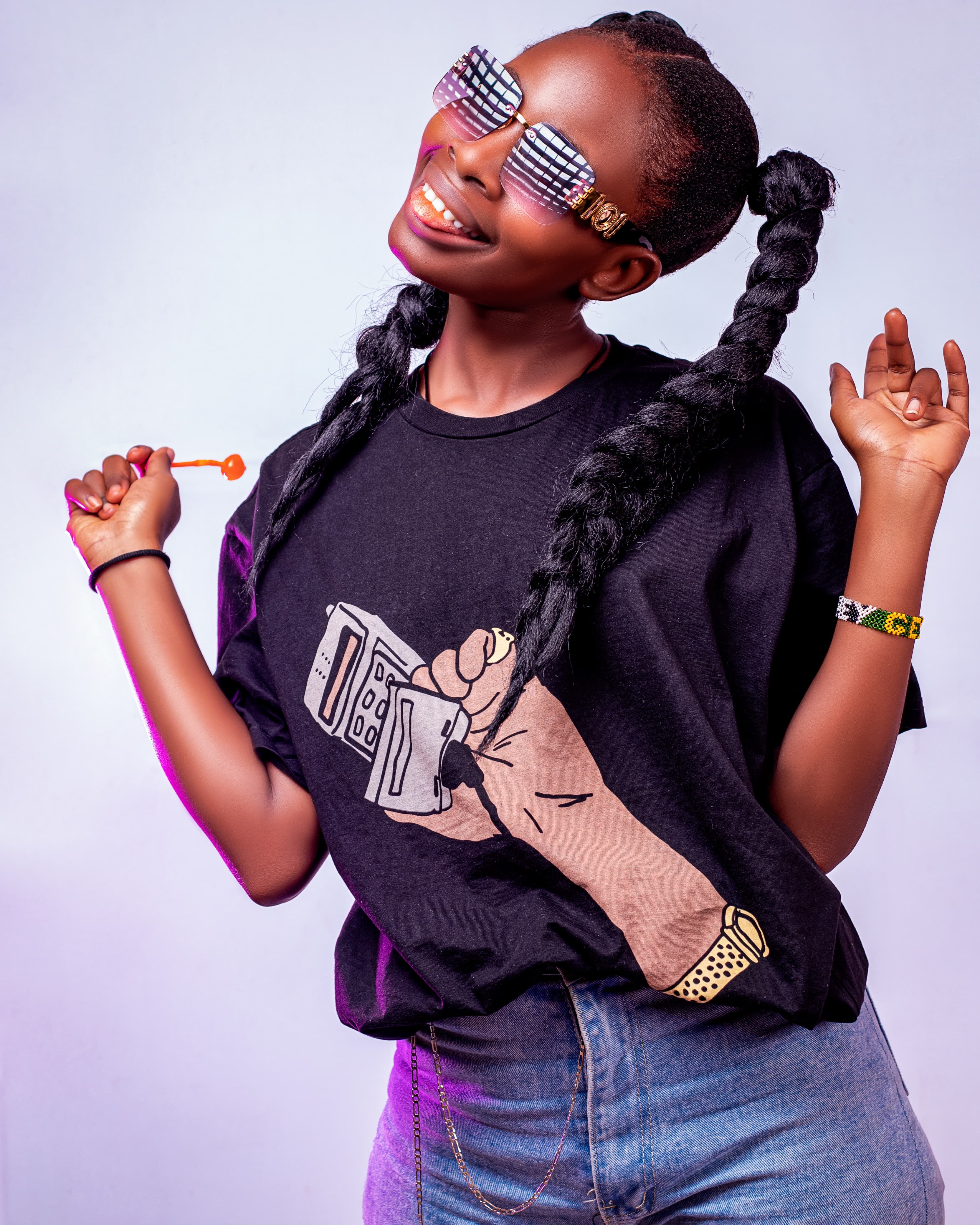 Fashionable woman with braids and graphic tee exudes fun and style in studio portrait.