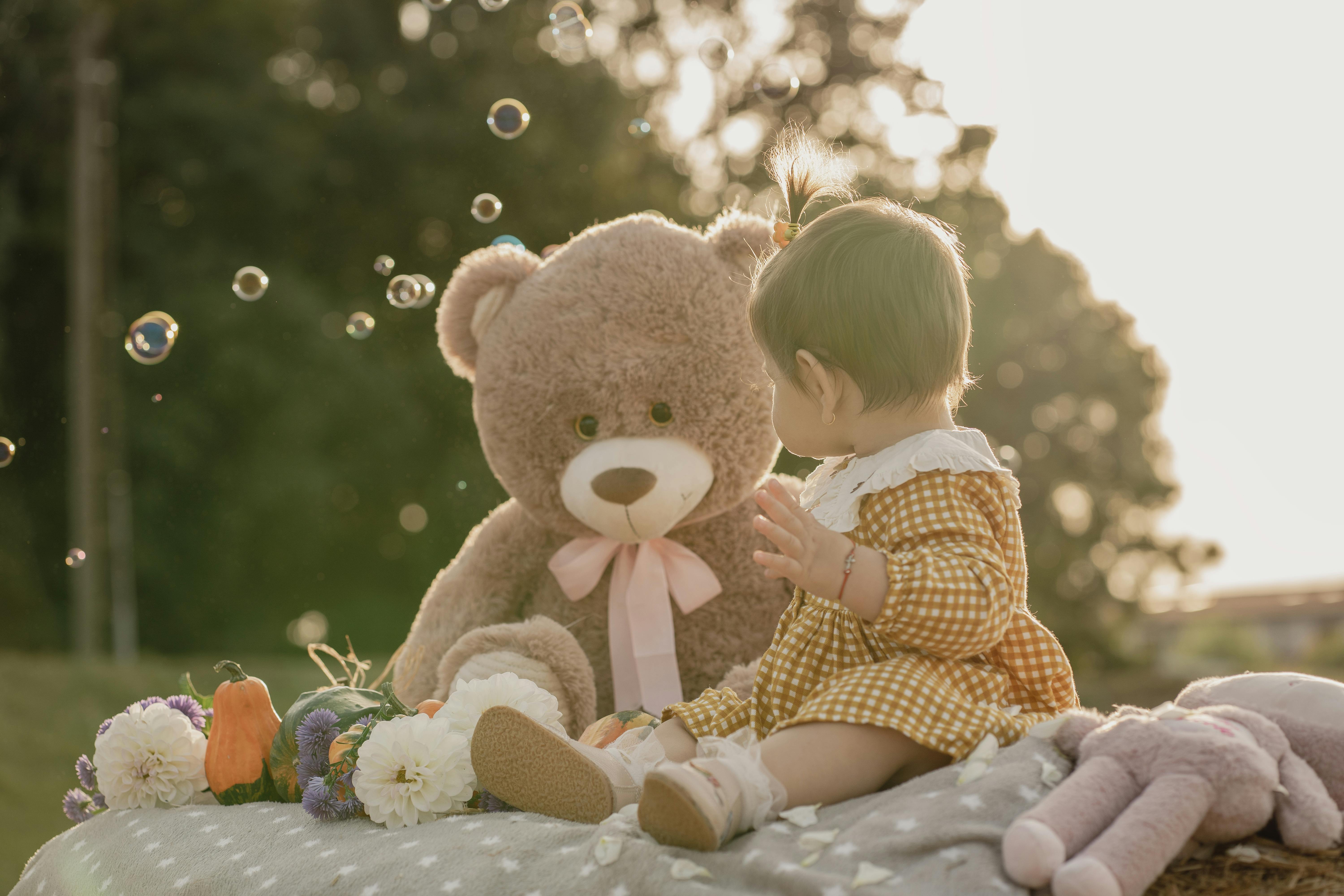 A heartwarming scene of a child with a teddy bear in nature, surrounded by flowers and bubbles.
