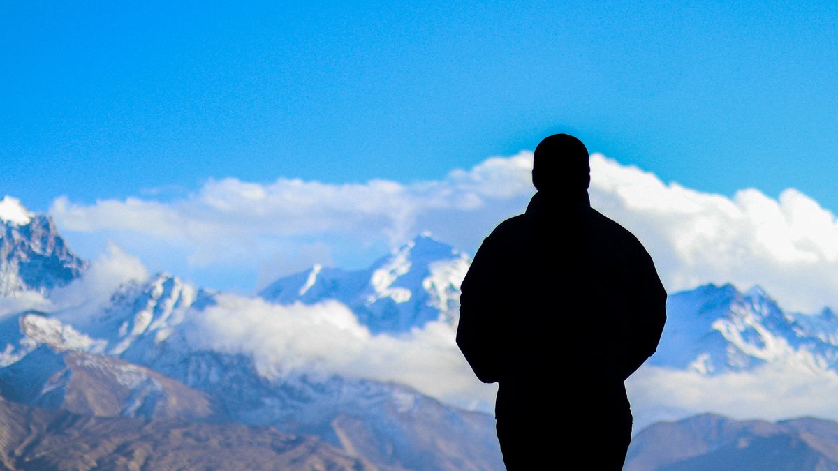 A figure standing in open mountain terrain, seen from behind