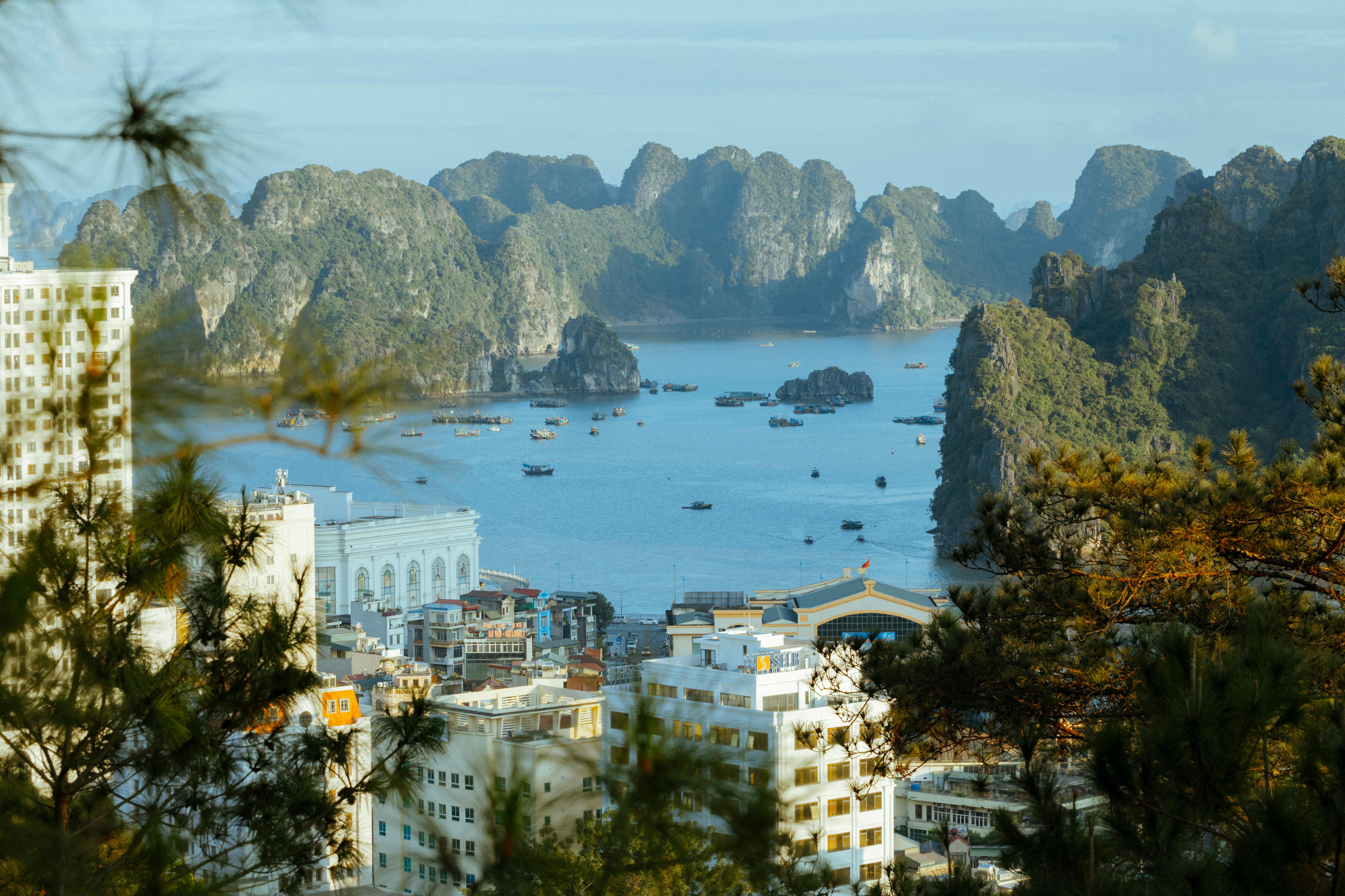 Aerial view of Halong Bay with city and rock formations under a clear sky. - Halong Bay