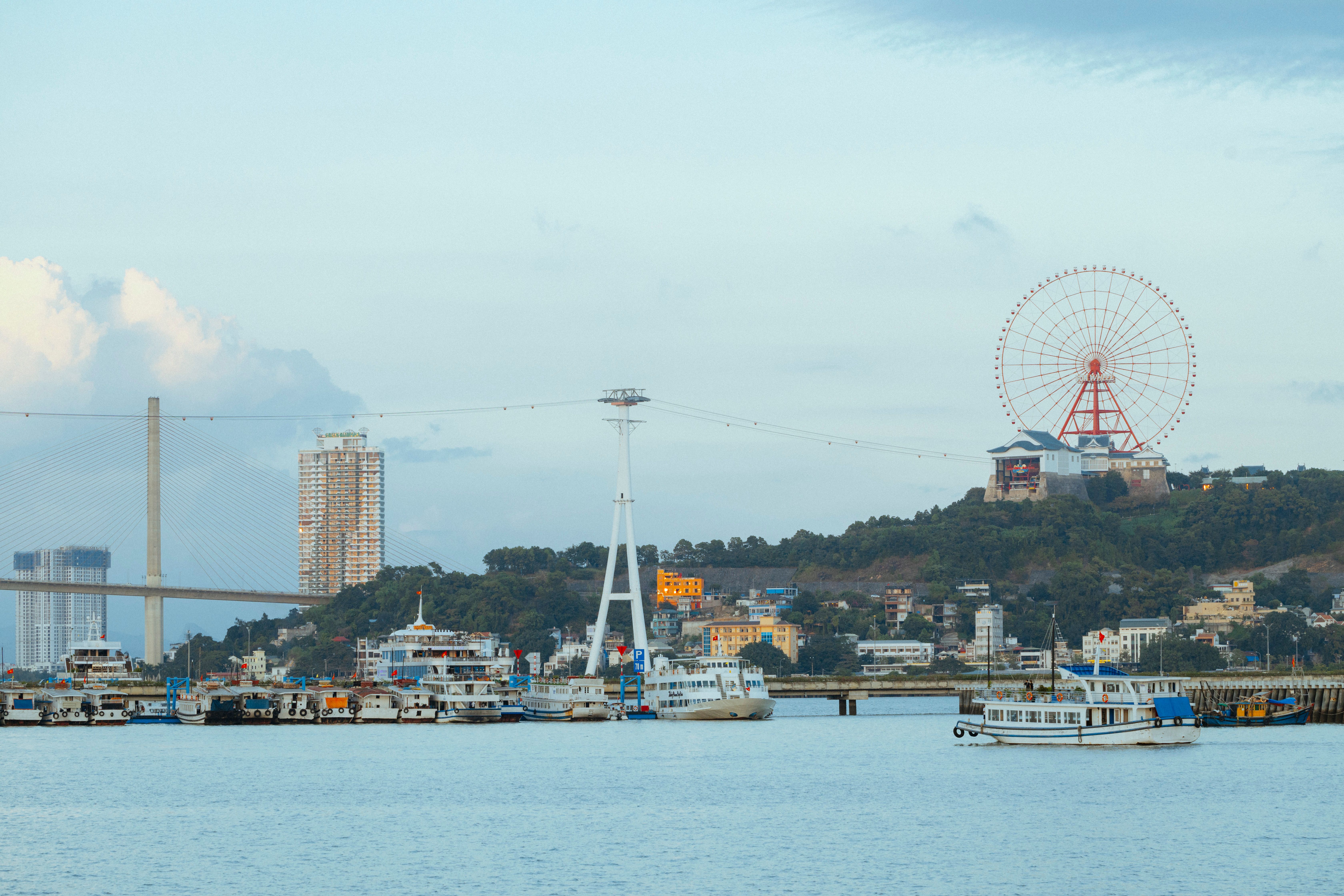Panoramic view of Ha Long Bay featuring a Ferris wheel, bridge, and ships.