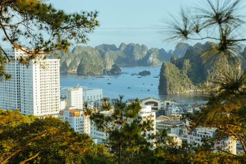 Free A scenic view of Ha Long Bay, Vietnam, showcasing urban buildings against a backdrop of natural karst formations. Stock Photo