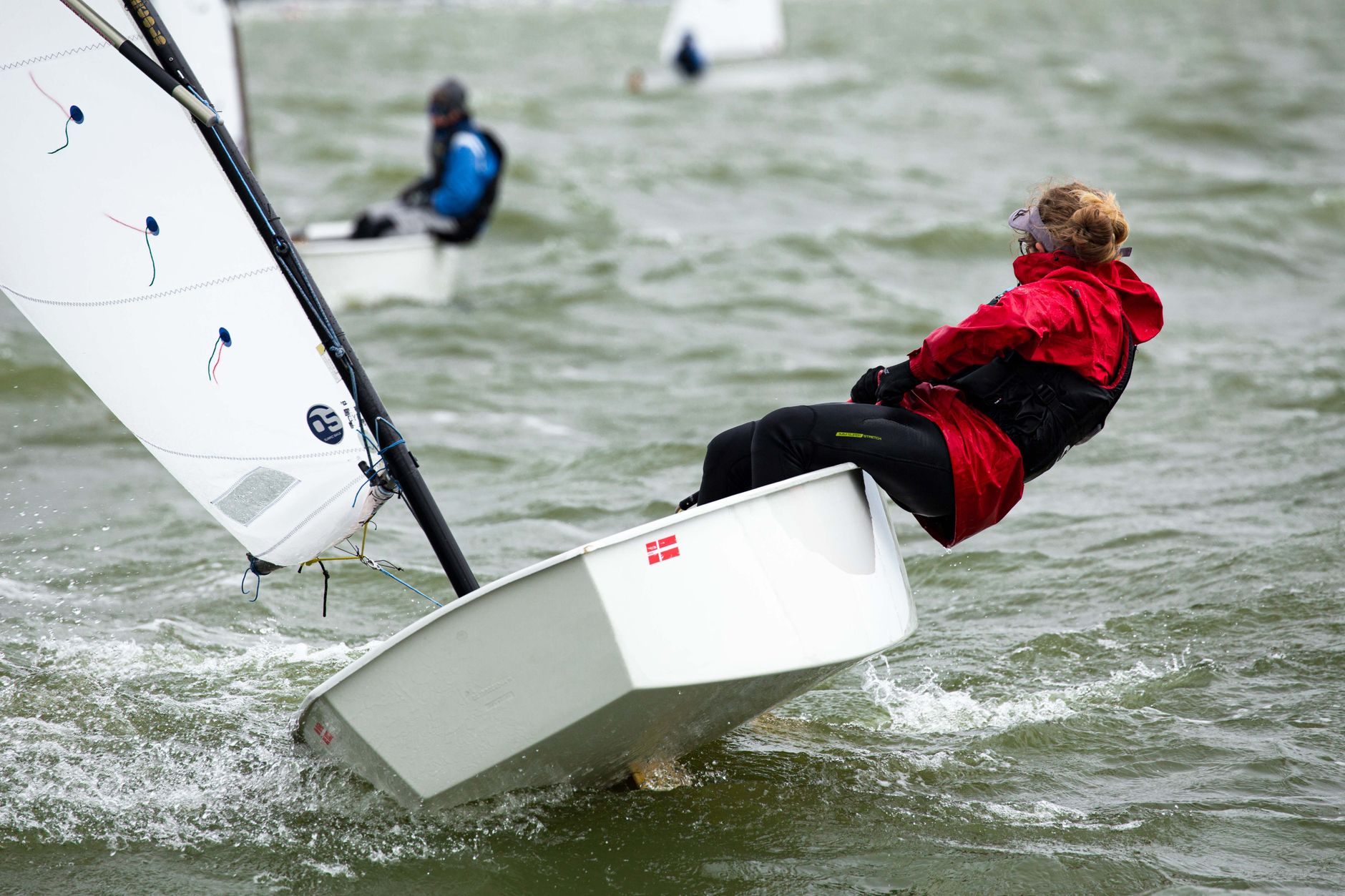 Dynamic scene of sailors racing sailboats on the open sea, capturing intense action and skill.