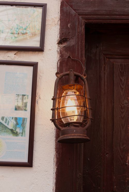 Free Close-up of an antique lantern hanging next to framed art on a rustic wooden door. Stock Photo