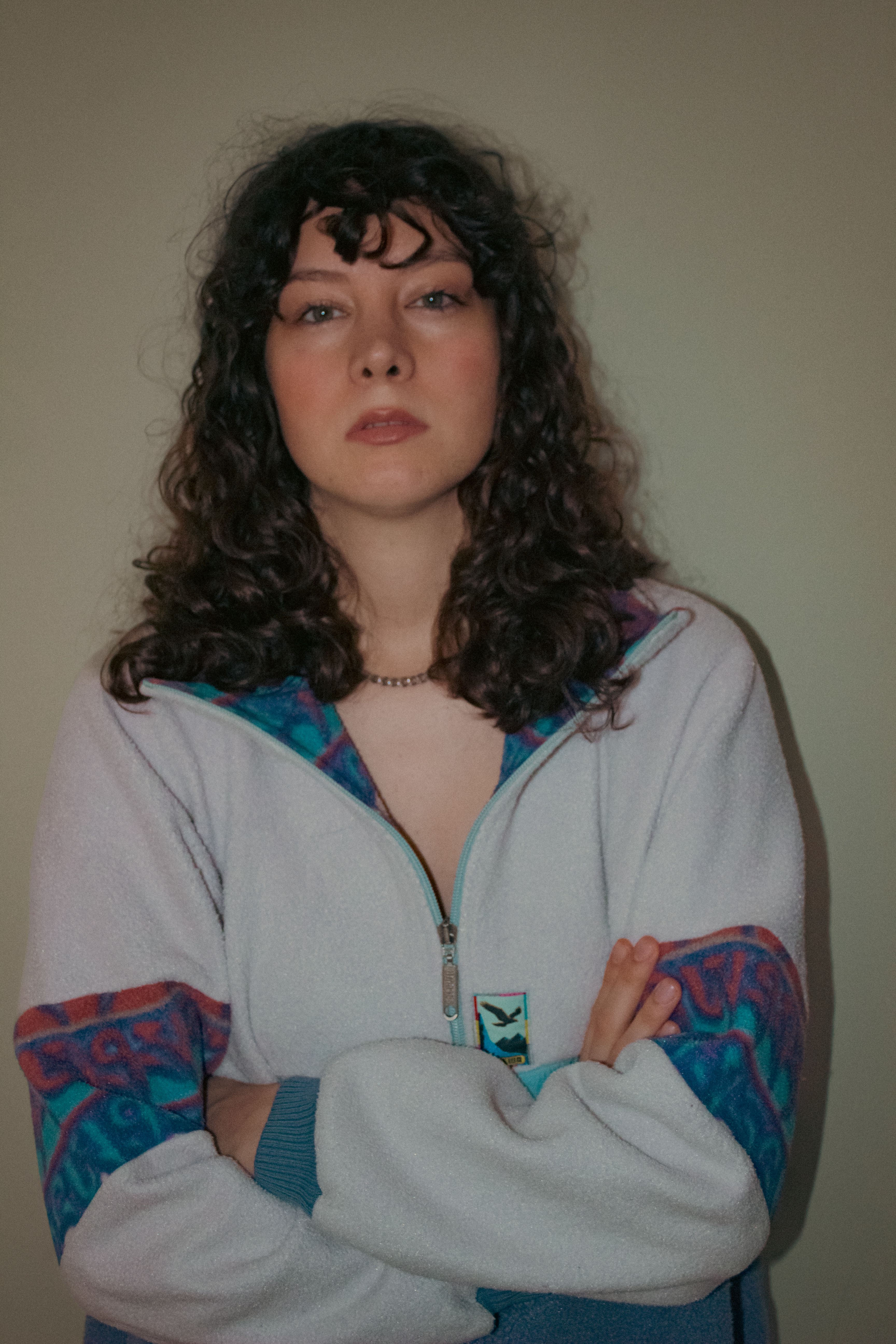 Portrait of a fashionable woman with long curly hair standing with crossed arms, Ankara, Türkiye.