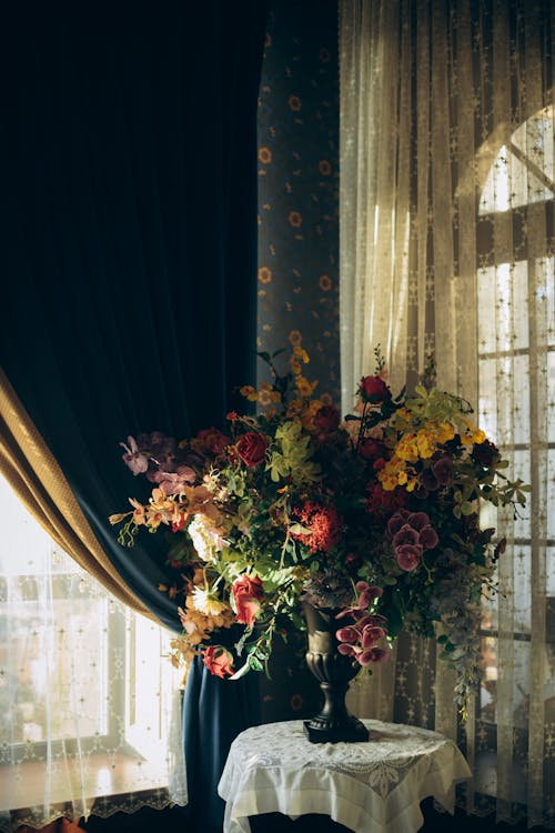 Flowers in Vase on Table near Curtain