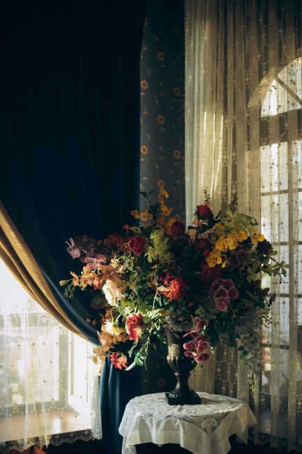 Beautiful bouquet of flowers in a vase by a window with curtains.