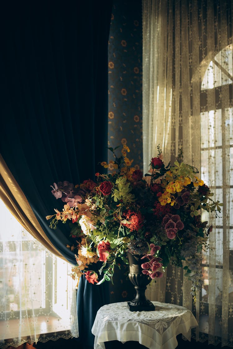 Flowers In Vase On Table Near Curtain