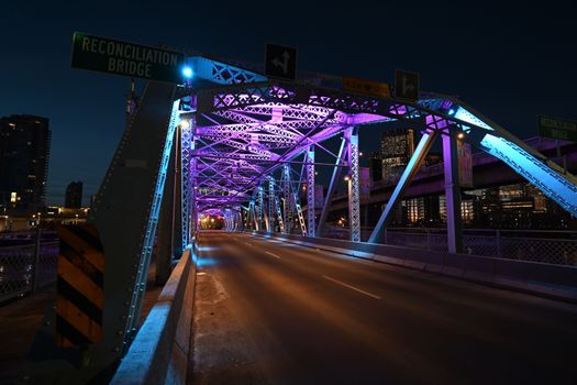 Stunning night view of Reconciliation Bridge in Calgary, Alberta, Canada, with vibrant purple lights.