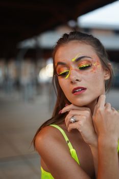 Portrait of a woman with bright makeup and expressive pose, showcasing unique artistry.