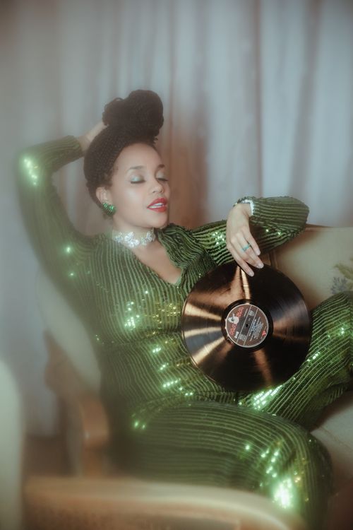 Free Stylish woman in green sequins holds vinyl in vintage setting, eyes closed. Stock Photo