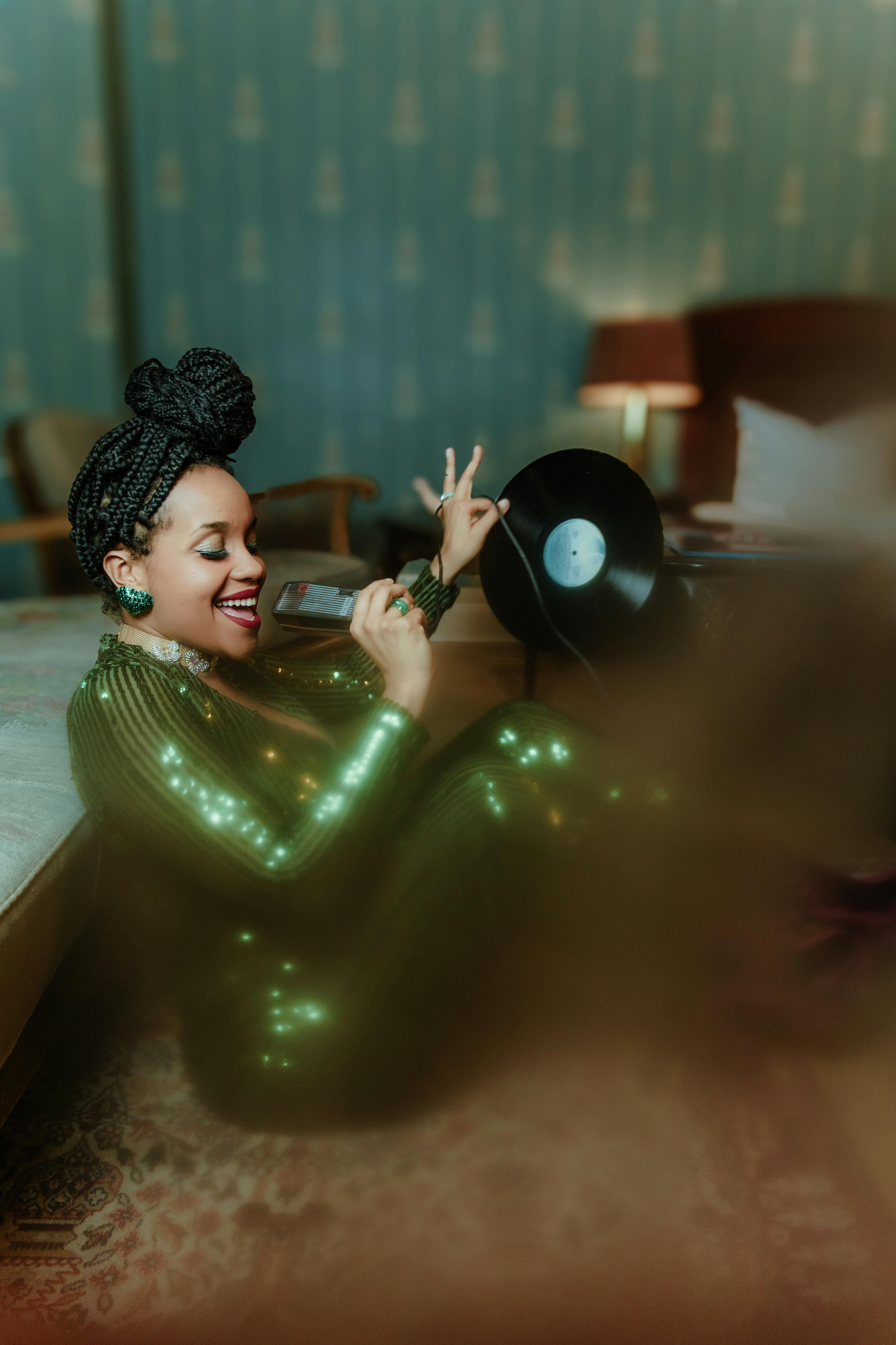 Stylish woman in glittery dress holding a vinyl record with a microphone indoors.