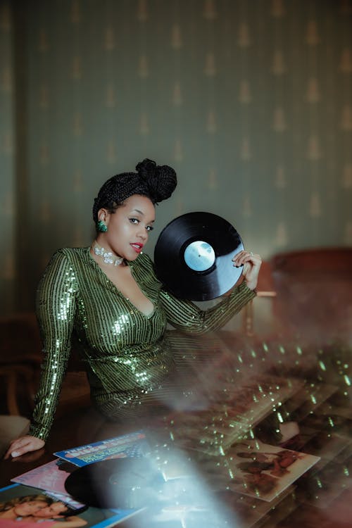 Woman in Green Clothes Sitting with Vinyl Disk