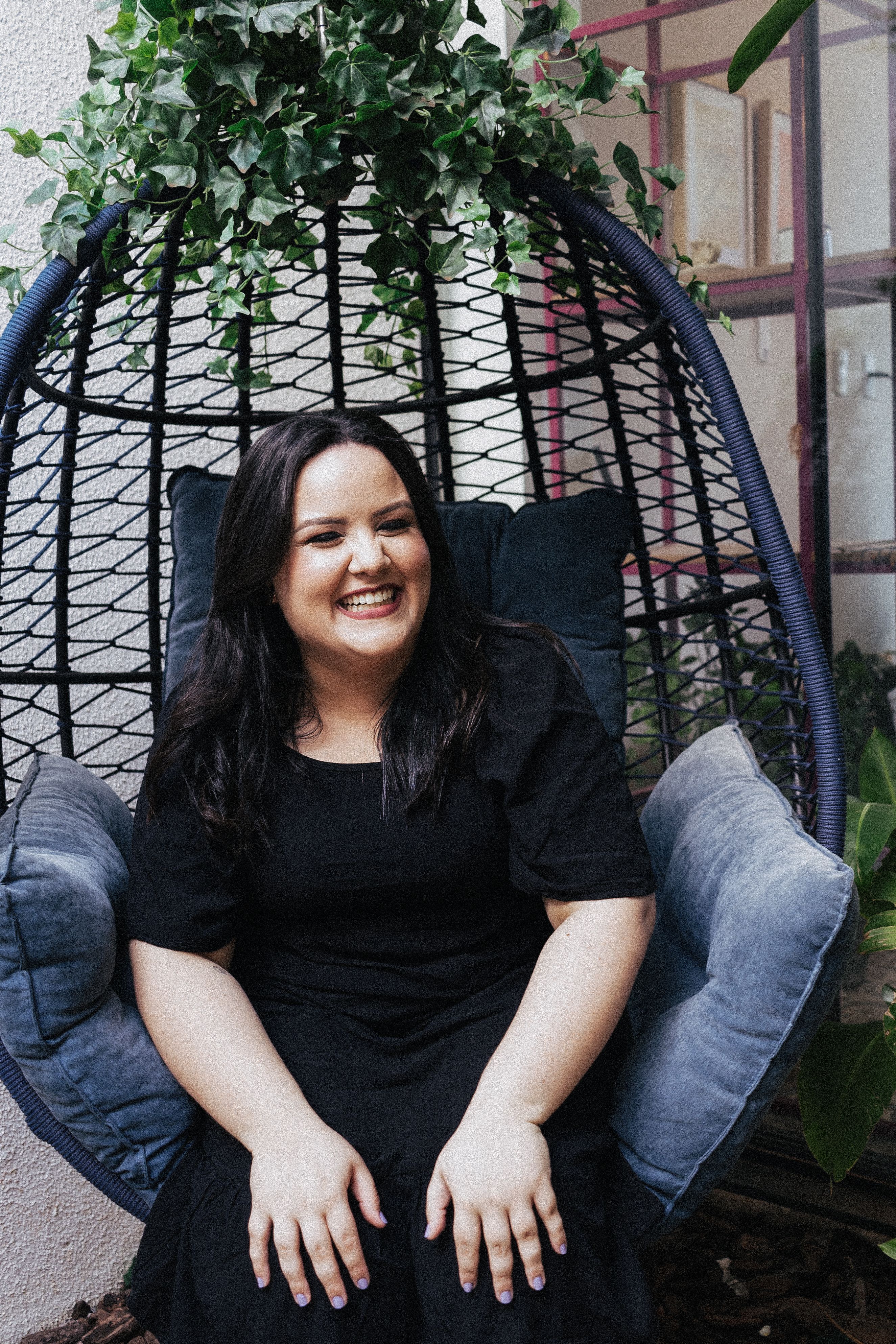 Laughing Woman in Black Dress Sitting in a Wicker Swing Egg Chair ...