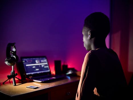 A teenager using a laptop with purple ambient lighting, symbolizing technology and modern living.