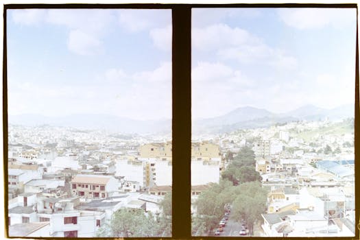 A vibrant cityscape view of buildings and mountains through a window frame.