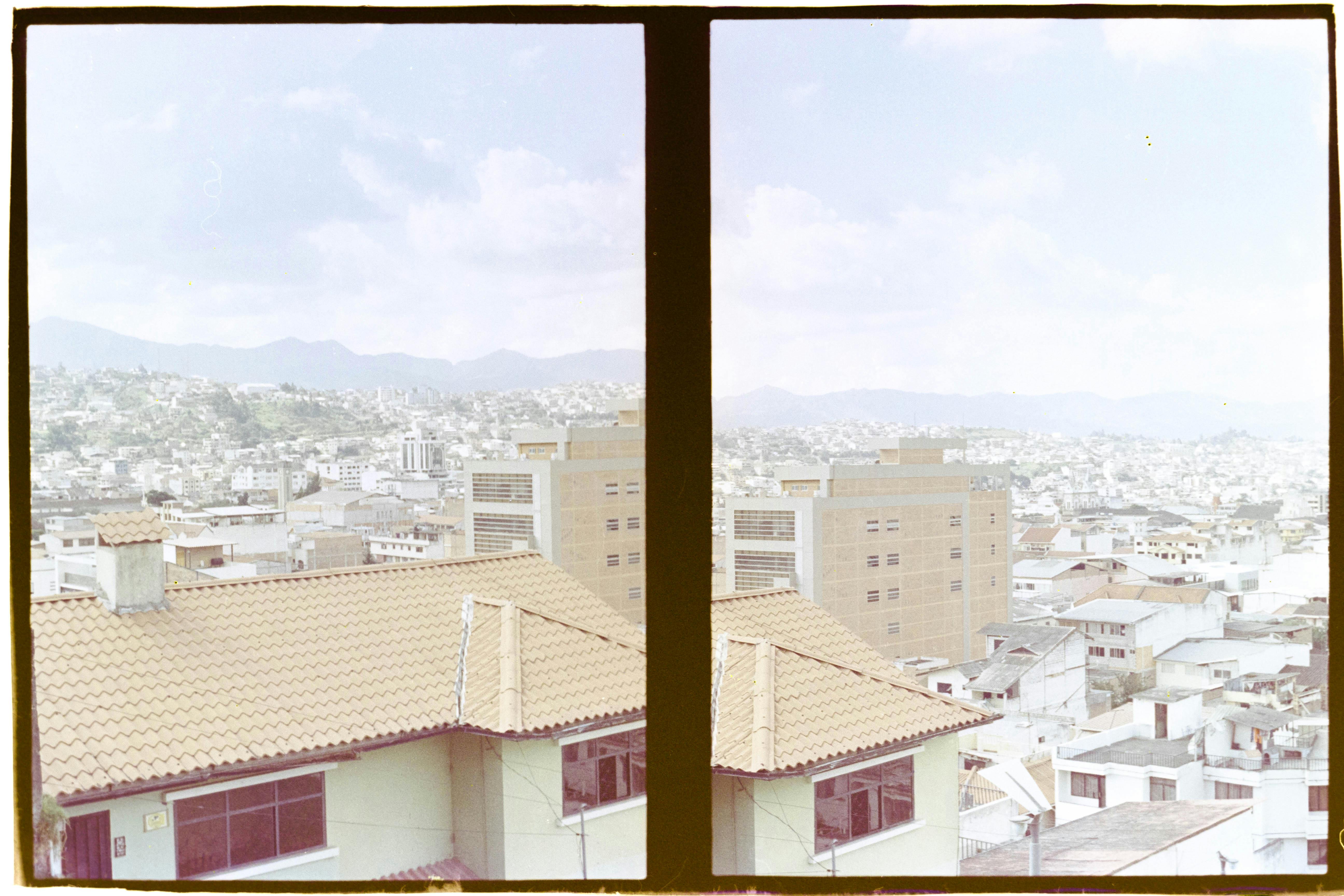 Vintage city skyline showcasing rooftops and distant hills through a film effect.