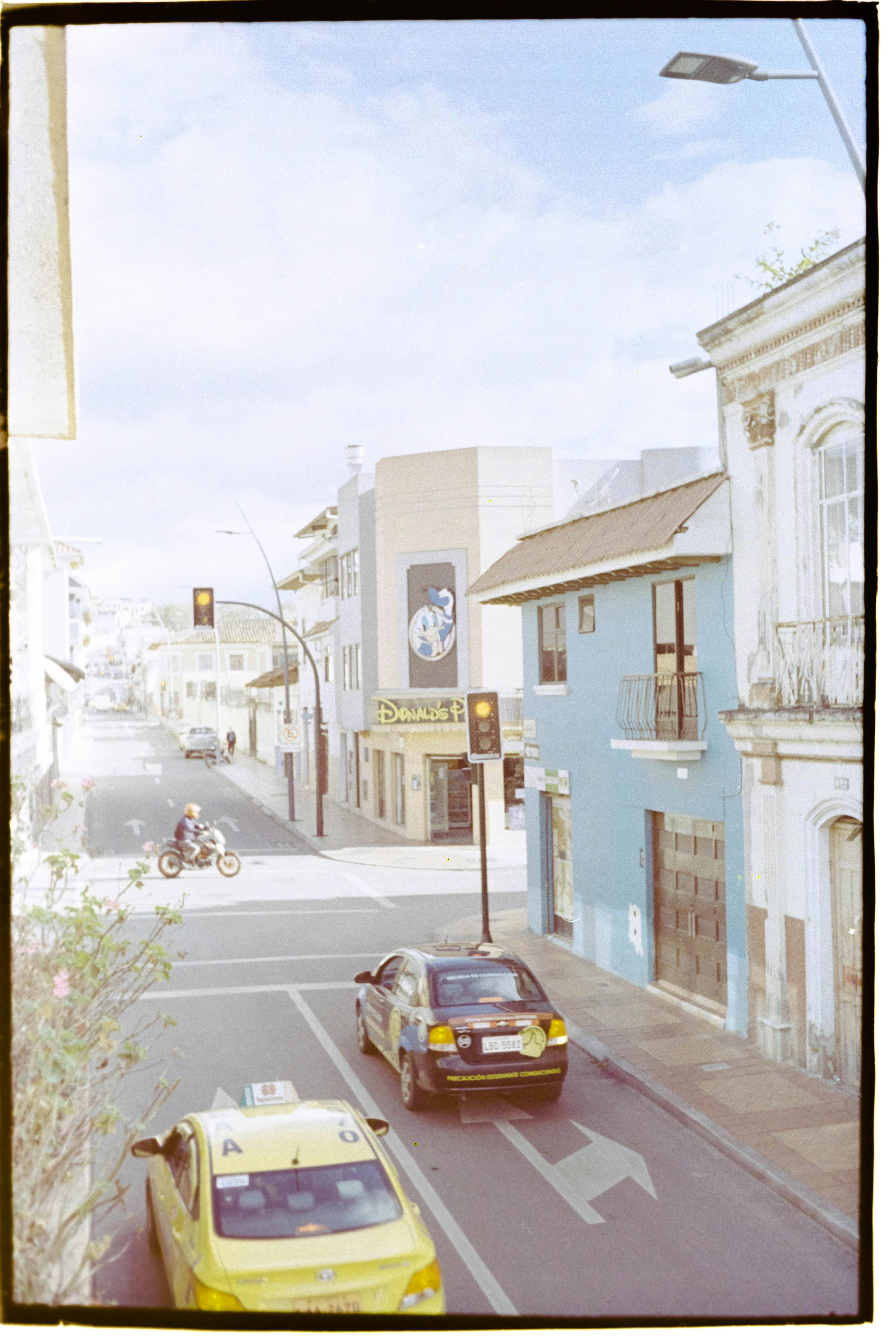 A bustling city street featuring cars, taxis, and vintage buildings under a clear sky.