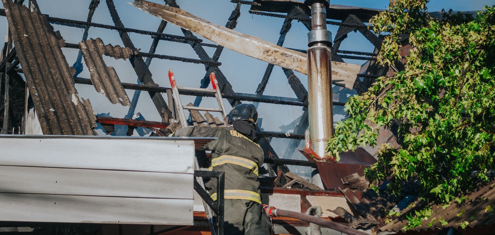 Firefighter clearing debris from a burned roof