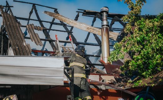 Firefighter clearing debris from a burned roof