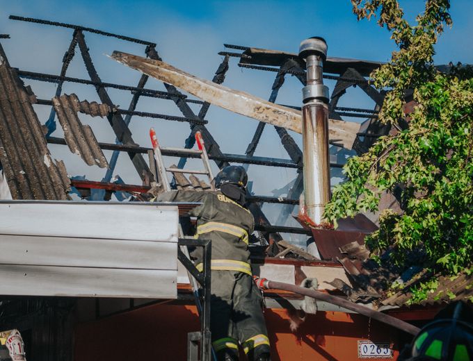 Firefighter clearing debris from a burned roof