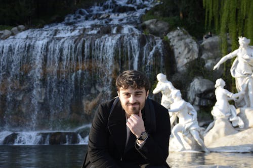 A man sitting in front of a fountain and a waterfall