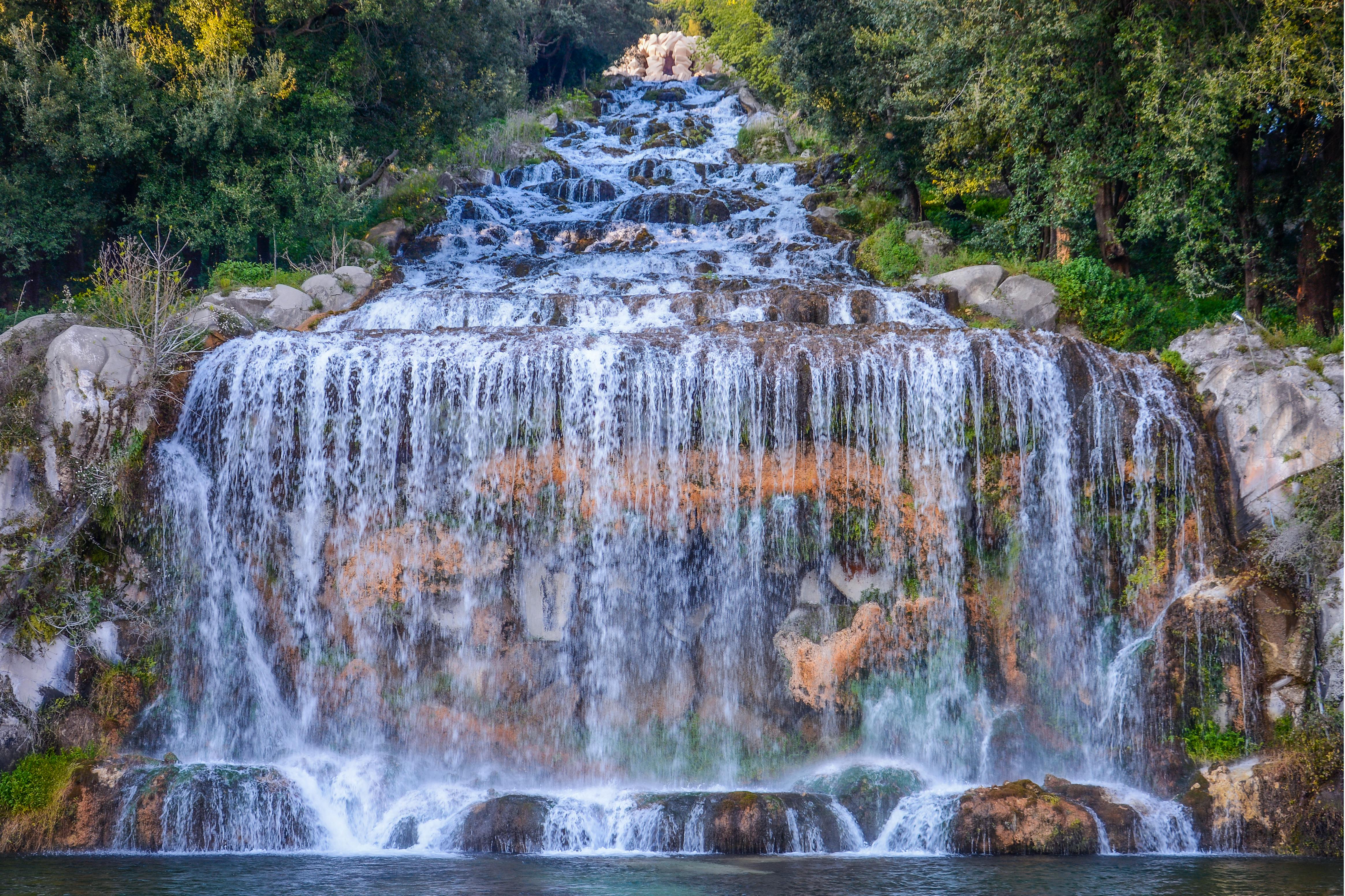 a waterfall is surrounded by trees and bushes