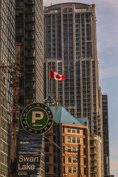 A Canadian flag waves among towering skyscrapers in downtown Toronto.