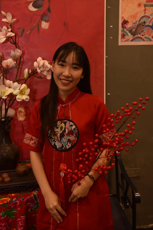 Smiling Woman in Traditional Clothing Standing with Artificial Flowers