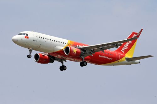 Free VietJet Air airplane flying with a clear sky background, showcasing vibrant branding. Stock Photo
