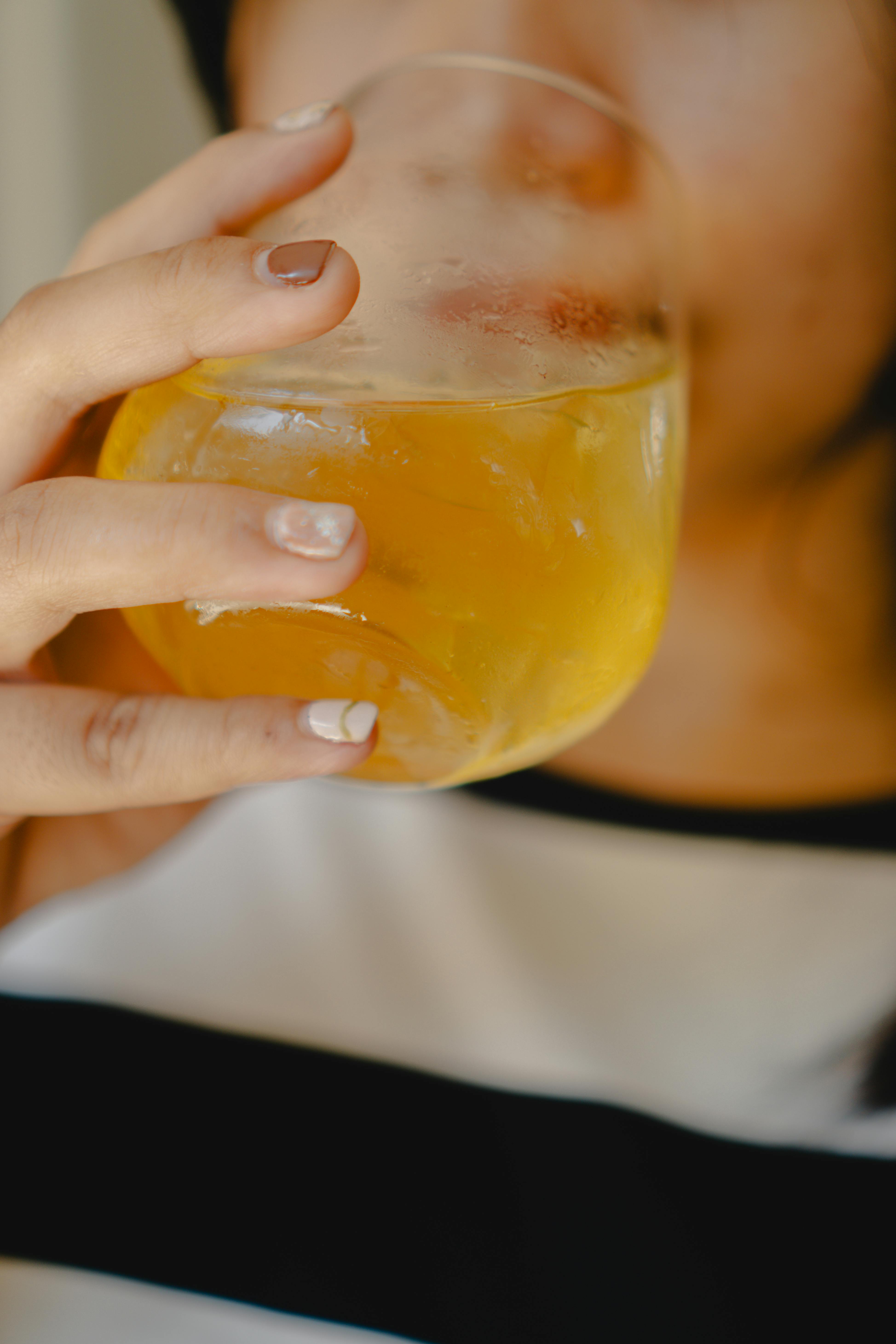 Close-up of an adult enjoying a refreshing glass of juice indoors. Captured in Madiun, Indonesia.