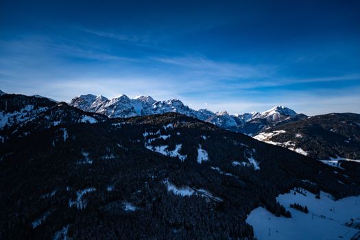 A stunning aerial view of snowcapped mountains with blue sky backdrop, capturing nature's serene beauty.