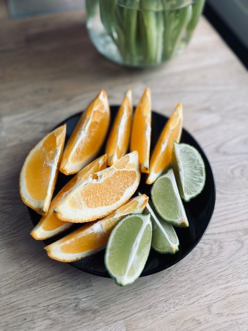 Free Close-up of fresh orange and lime slices on a black plate. Stock Photo