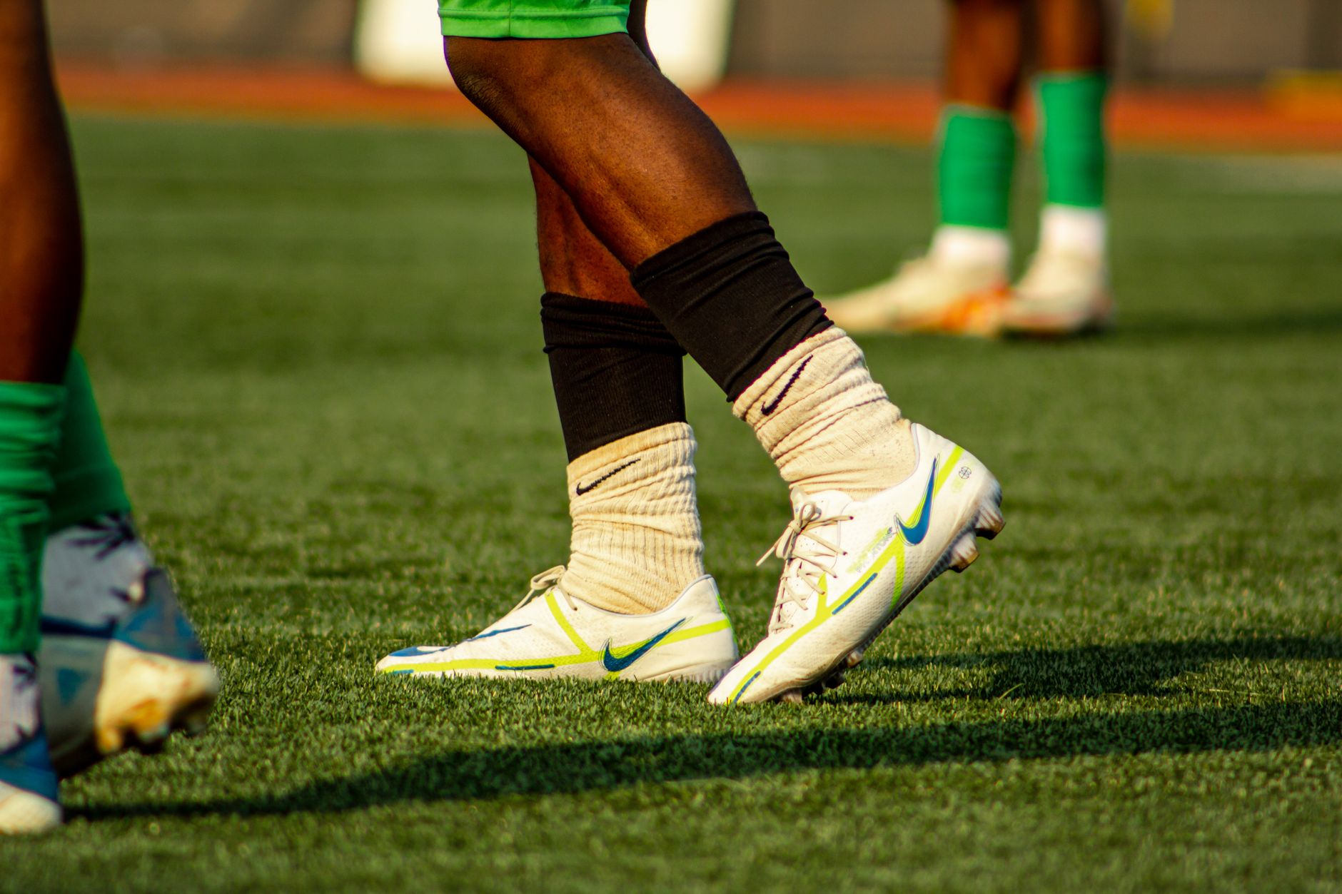 Soccer players training on a grass field in bright cleats and socks.