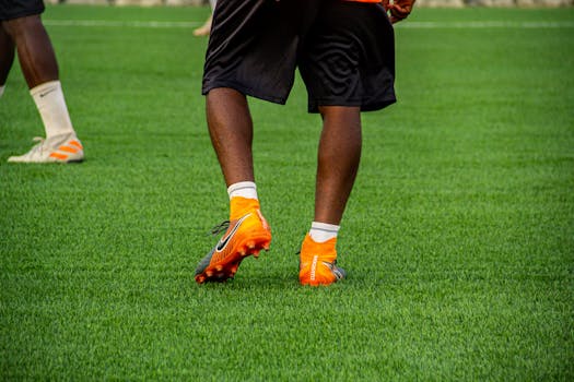 Close-up of a soccer player's legs and shoes on a field in action.