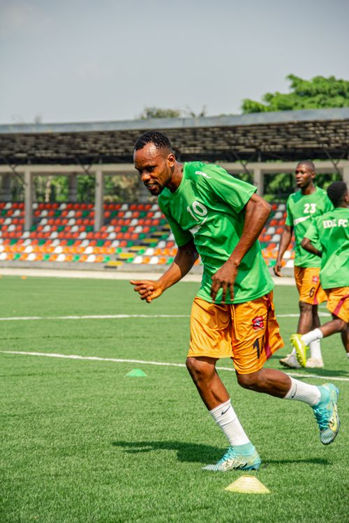 Free Athletes in green jerseys engage in a dynamic football training session on a vibrant outdoor field. Stock Photo