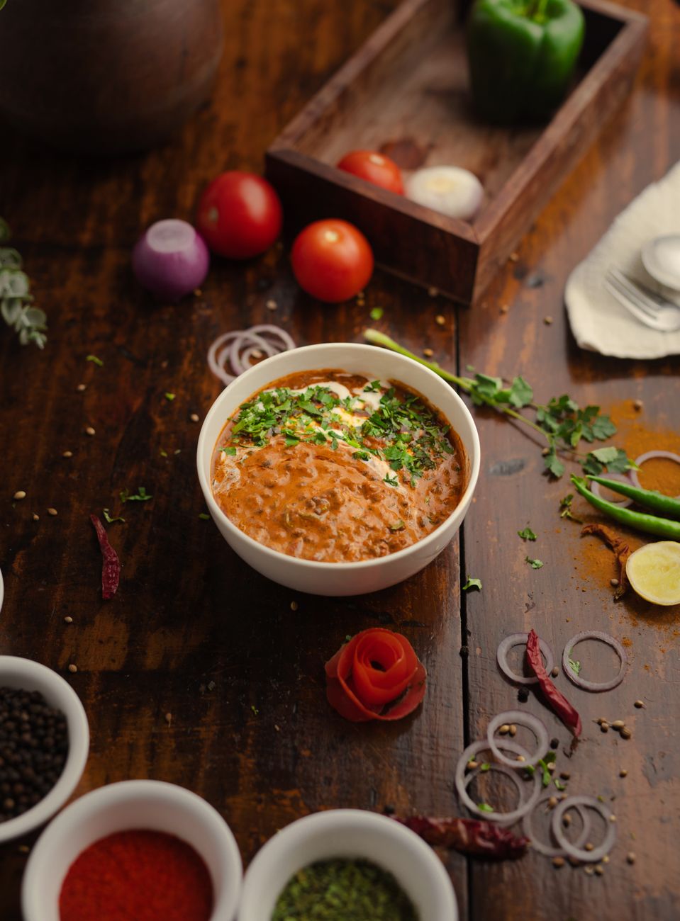 A bowl of creamy orange-red lentil dal garnished with fresh cilantro, served alongside rice