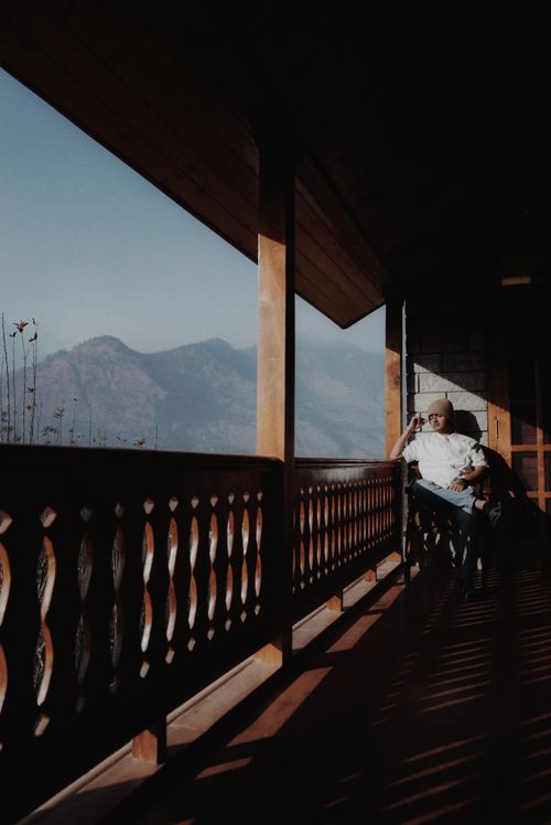 Free Man relaxing on a wooden terrace with a mountain view, enjoying the tranquil setting. Stock Photo