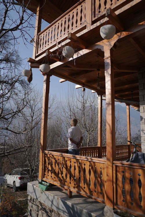 Free Back view of a person standing on a wooden terrace, surrounded by serene nature. Stock Photo