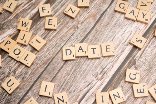 Free Scrabble tiles on wood spelling 'Date', creating a playful and creative scene. Stock Photo