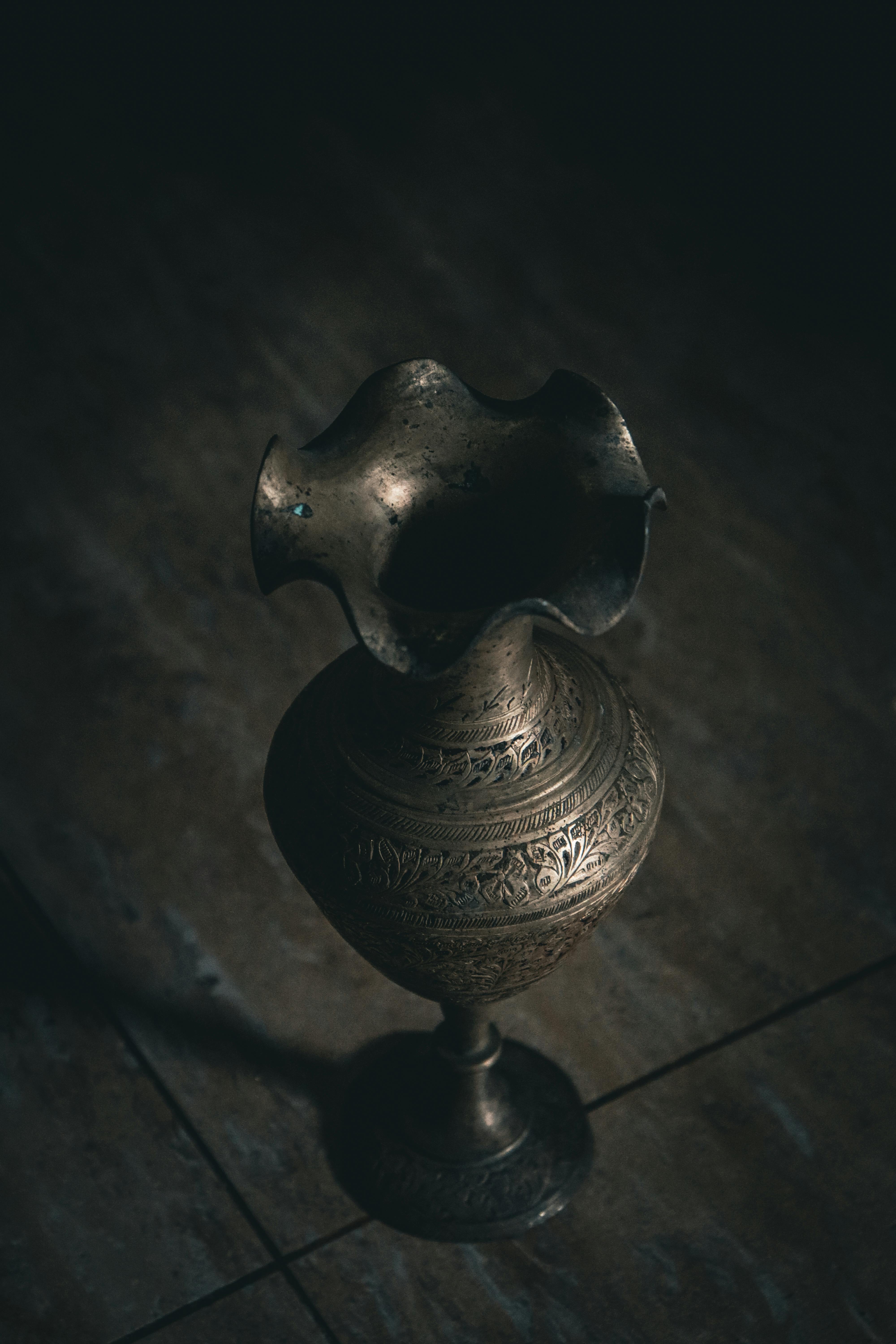 Free Moody high-angle view of a vintage brass vase on a rustic wooden floor. Stock Photo
