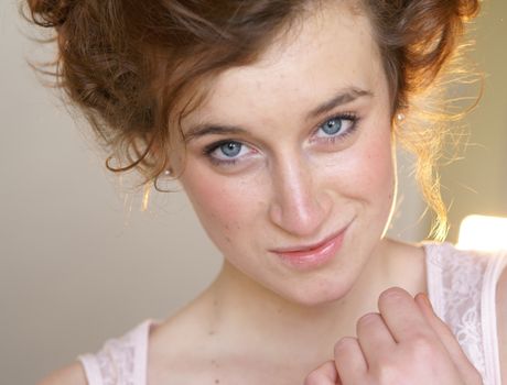 Close-up portrait of a young woman with curly hair, smiling softly.