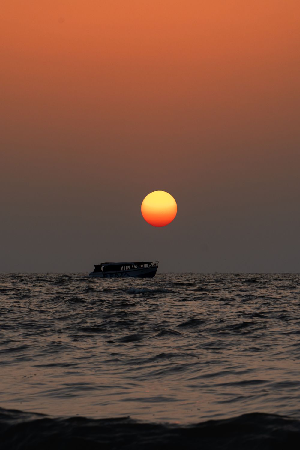 Silhouetted Boat on a Sea at Sunset · Free Stock Photo