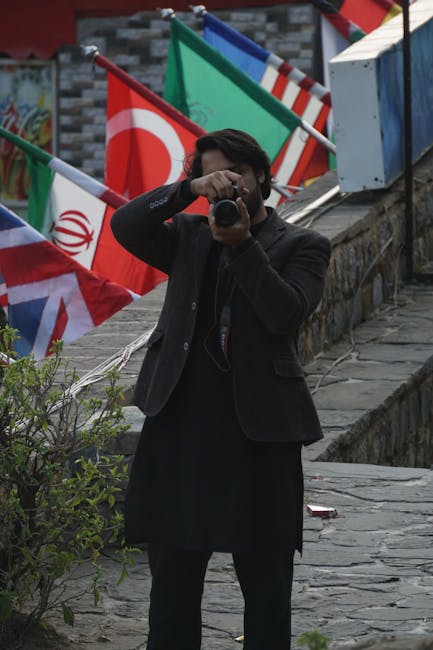 A man photographing outdoors in Saidpur Village, Islamabad with flags in the background.